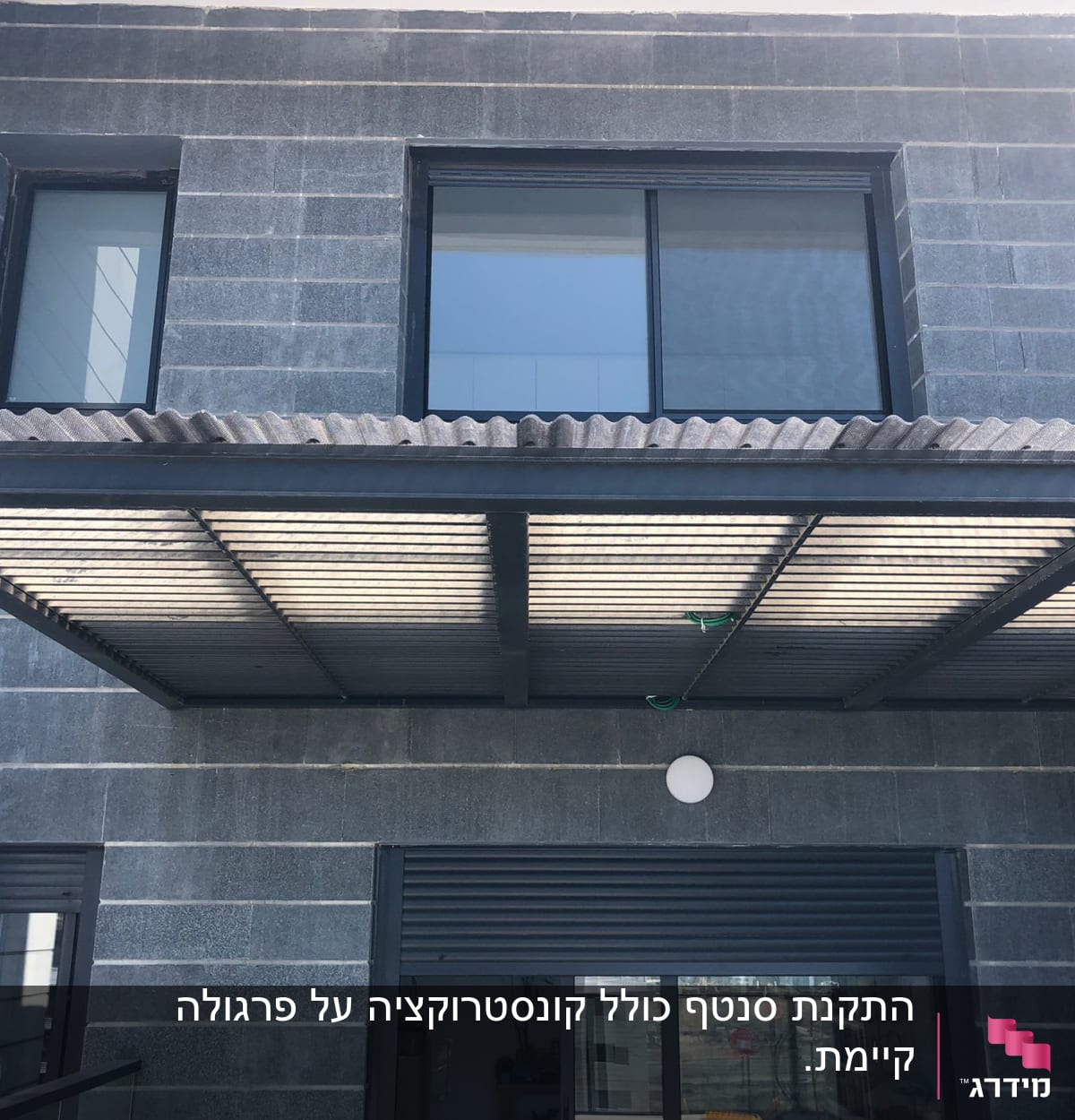 גג מתכת מעל חלון גדול עם תריסים